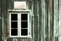 Abandoned house with old peeling grey and green wooden wall and grunge broken white window without glasses