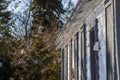 Abandoned house - windows blocked, electricity wires cut, snow covered field with trees in the background. Spring, sunny day. Royalty Free Stock Photo