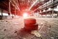 An abandoned industrial interior in grey colors. Two old tyres in a center. Broken windows and high roof. Old warehouse. Royalty Free Stock Photo