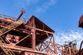 Abandoned industrial site, stairs and open walkways with rusted metal and peeling paint against a beautiful blue sky