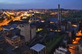 Abandoned ironworks factory in the dark with a shining city in the background