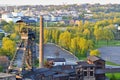 Abandoned ironworks factory with a mining tower and trees and city in the background