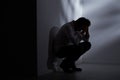 Abandoned man sitting beside wall