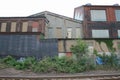 Abandoned Manufacturing Buildings With Painted Layers and Boarded Up Windows Behind Train Tracks With Cloudy Sky