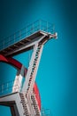 Abandoned metal diving structure. Iconic industrial and sports architecture, white and red steel elements on a deep blue clear sky