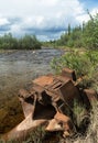 Abandoned mining equipment rusting along fast flowing Alaskan st Royalty Free Stock Photo