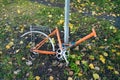 Abandoned old bicycle without wheels, chained to metal pole with blue locker.