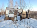 Abandoned old broken house in a deaf birch winter forest. Wooden old house. No roof. Without a door. A decrepit building