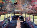 Abandoned old bus with colorful cool graffiti in a field during daytime