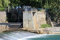 Abandoned old dam with dilapidated stone and concrete walls and rusted cogwheels on top used to provide power for industrial