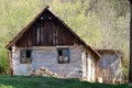 Abandoned old dilapidated small wooden house with broken windows and chopped pile of firewood in front located on top of hill