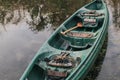 Abandoned old green plastic canoe with paddle beside the lake background. Royalty Free Stock Photo