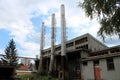 Abandoned old industrial complex building with destroyed backyard wall next to three tall metal chimneys Royalty Free Stock Photo