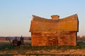 Abandoned old log barn and harvester in fall Royalty Free Stock Photo