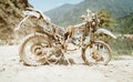 Abandoned old motocross Motorcycle be drowned in deep road dust near the crowed town road in Ramechhap, Nepal