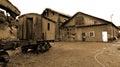 An old rotten and rusty lost in time waggon standing next to an deteriorated shed [Sepia] Royalty Free Stock Photo