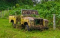 Abandoned old and rusted car decaying in the middle of the green rain forest in Volcan Arenal in Costa Rica