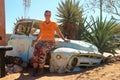 Abandoned old rusty cars in the desert of Namibia and a plump white tourist girl near the Namib-Naukluft National Park