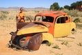 Abandoned old rusty cars in the desert of Namibia and a plump white tourist girl near the Namib-Naukluft National Park Royalty Free Stock Photo