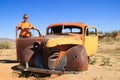 Abandoned old rusty cars in the desert of Namibia and a plump white tourist girl near the Namib-Naukluft National Park Royalty Free Stock Photo