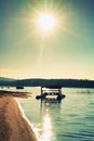 Abandoned old rusty paddle boat stuck on sand of beach. Wavy water level, island on horizon.