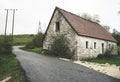 Abandoned old stone rural house. Village house. Derelict haunted stone house and dirt road in the woods. Tree white blossom Royalty Free Stock Photo