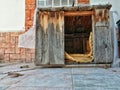 Abandoned old wood dog house with notable texture and brick wall background