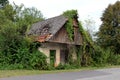 Abandoned old wooden house with broken doors and windows completely overgrown with crawler plants and other forest vegetation