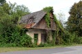 Abandoned old wooden house with broken doors and windows completely overgrown with crawler plants and other forest vegetation Royalty Free Stock Photo