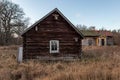 Abandoned old worn and weathered boarded wooden timber cottage house on grassy field.