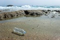 An abandoned plastic water bottle is lying on the beach.