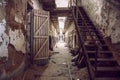 Abandoned prison cell walkway with old rusty stairs, doors and peeling walls.