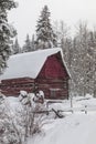 Abandoned red barn in winter scene covered in snow Royalty Free Stock Photo