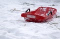 Abandoned red bobsled on snow