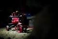 An abandoned red children`s tricycle stands under a layer of dust in the basement among a variety of junk. The concept