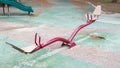 Abandoned red teeter totter and slides at a children`s outdoor playground Royalty Free Stock Photo