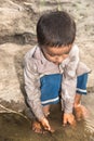 Abandoned refugee boy drinking water from river and clothes are dirty and his eyes are full of pain Royalty Free Stock Photo