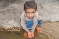 Abandoned refugee boy drinking water from river and clothes are dirty and his eyes are full of pain Royalty Free Stock Photo