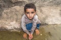 Abandoned refugee boy drinking water from river and clothes are dirty and his eyes are full of pain Royalty Free Stock Photo