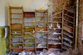 An abandoned room with a wooden bookshelf filled with old books and objects, and a crumbling brick wall. Old shelves for papers in