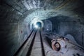 Abandoned round underground mine tunnel with remnant of equipment, pipeline and narrow-gauge railway Royalty Free Stock Photo