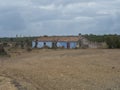 Abandoned ruined blue house at country dirt road through bare field with and dry trees near Odeceixe, Portugal. Cloudy Royalty Free Stock Photo