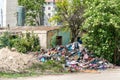 Abandoned rural damaged house in the ghetto near new residential building in the city used as garbage dump with junk and litter in Royalty Free Stock Photo