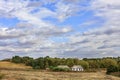 An abandoned rural house stands on the side of a rural road at the edge of a field under a cloudy sky Royalty Free Stock Photo