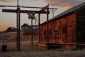 Abandoned russian village. Courtyard of old wooden house, barn with closed shutters in red warm light of sun, with shadows Royalty Free Stock Photo