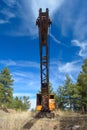 Abandoned Rusting Antique Orange and Black Crane with Blue Sky at a Low Angle