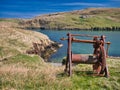 An abandoned, rusting boat winch with beach below in Shetland, UK Royalty Free Stock Photo
