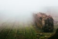 Abandoned rusting train and empty train tracks photographed in a foggy day