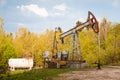 Abandoned rusty broken oil pump and pipeline equipment in forest, oil extraction rig, spring evening