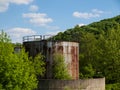 Abandoned rusty metal silo with concrete wall